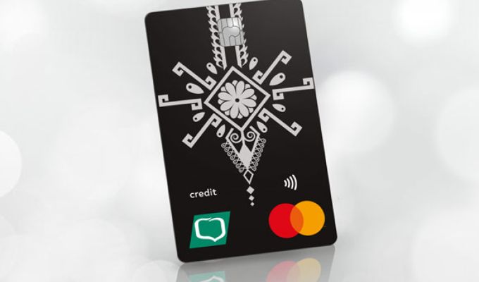 Czarna karta kredytowa MasterCard Credit z białym folkowym wzorem oraz z logo Grupy BPS, ustawiona w pionie pod kątem na jasnym, rozmytym tle.